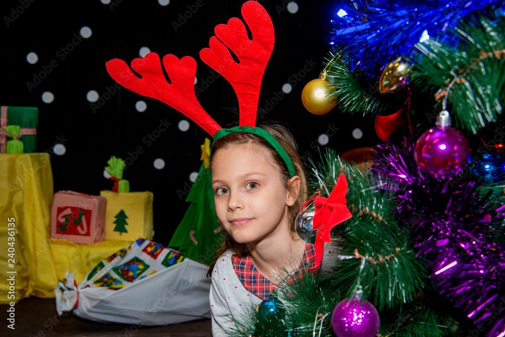 Cute little girl posing next to the christmas trees with horns