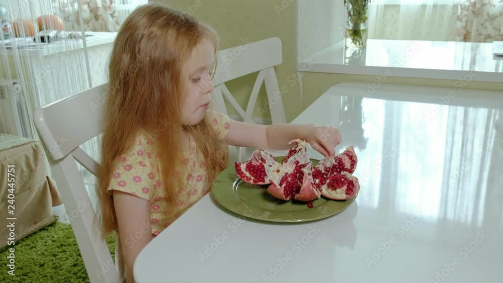 happy little girl with blond hair eats pomegranate, healthy food concept, close-up portrait happy little girl with blond hair eats pomegranate, healthy food concept, close-up portrait