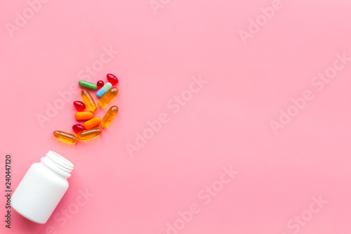 Close up of an open bottle of medicine and its lid. Several pills are lying on pink desk. Pharmacology and medical supplies. Top view mock-up