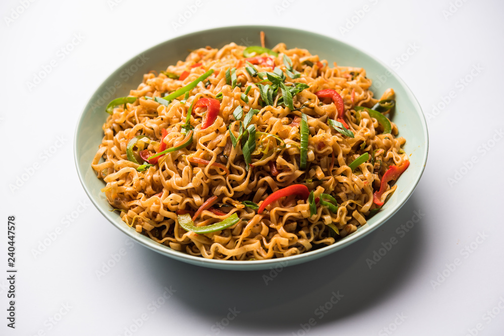 Schezwan veg noodles is a spicy and tasty stir fried flat Hakka noodles with sauce and veggies. served with chopsticks. selective focus Schezwan veg noodles is a spicy and tasty stir fried flat Hakka noodles with sauce and veggies. served with chopsticks. selective focus