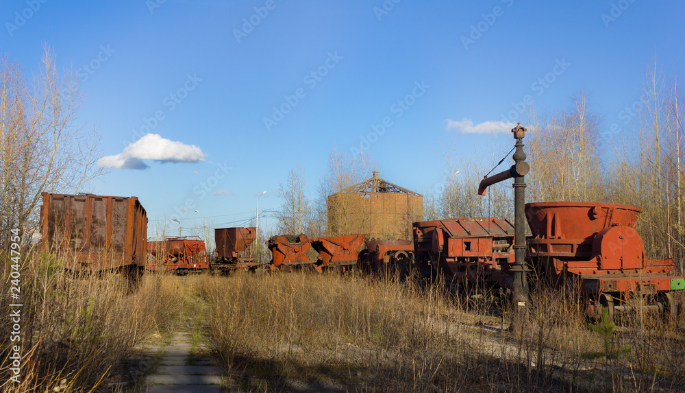 Obraz premium Old hydrocolumn for charging steam locomotives with water. Railway train of industrial carts for servicing mining and smelting plant