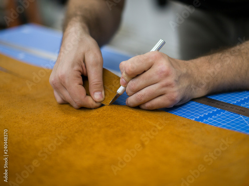 Close up of a shoemaker cutting leather in a workshop. Handmade leather craft concept.