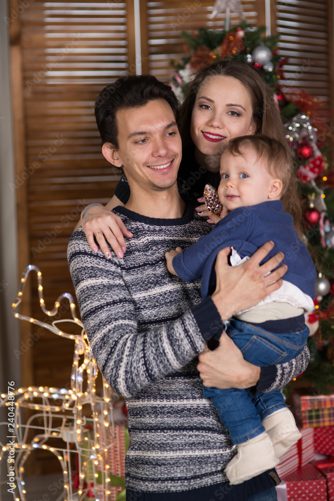 Obraz premium family sits with the baby sitting near the Christmas tree,