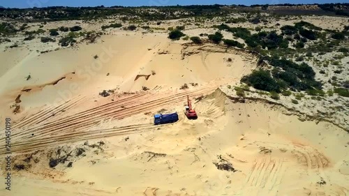 aerial picture huge sand pit with truck near operating excavator by ground road under blue sky