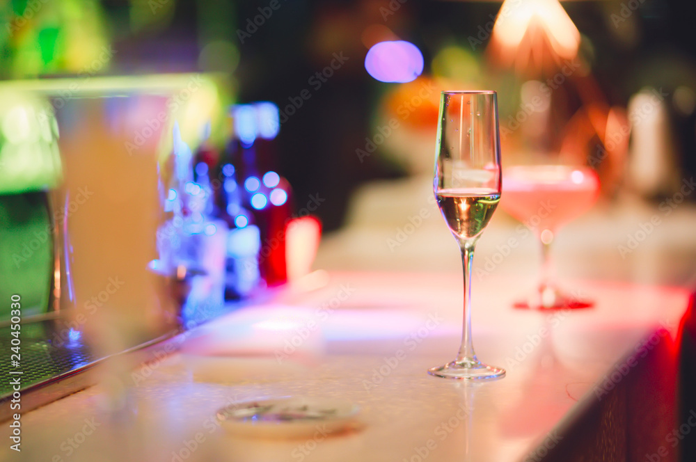 Champagne glass drink-beverage on a bar. Selective focus on the foreground  glass,night background . Blurred people in the background. Trendy black  stylish edit. Copy paste space for design concept Stock Photo |