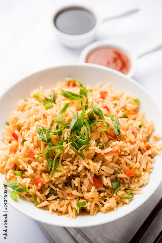 Schezwan Fried Rice Masala is a popular indo-chinese food served in a plate or bowl with chopsticks. selective focus Schezwan Fried Rice Masala is a popular indo-chinese food served in a plate or bowl with chopsticks. selective focus