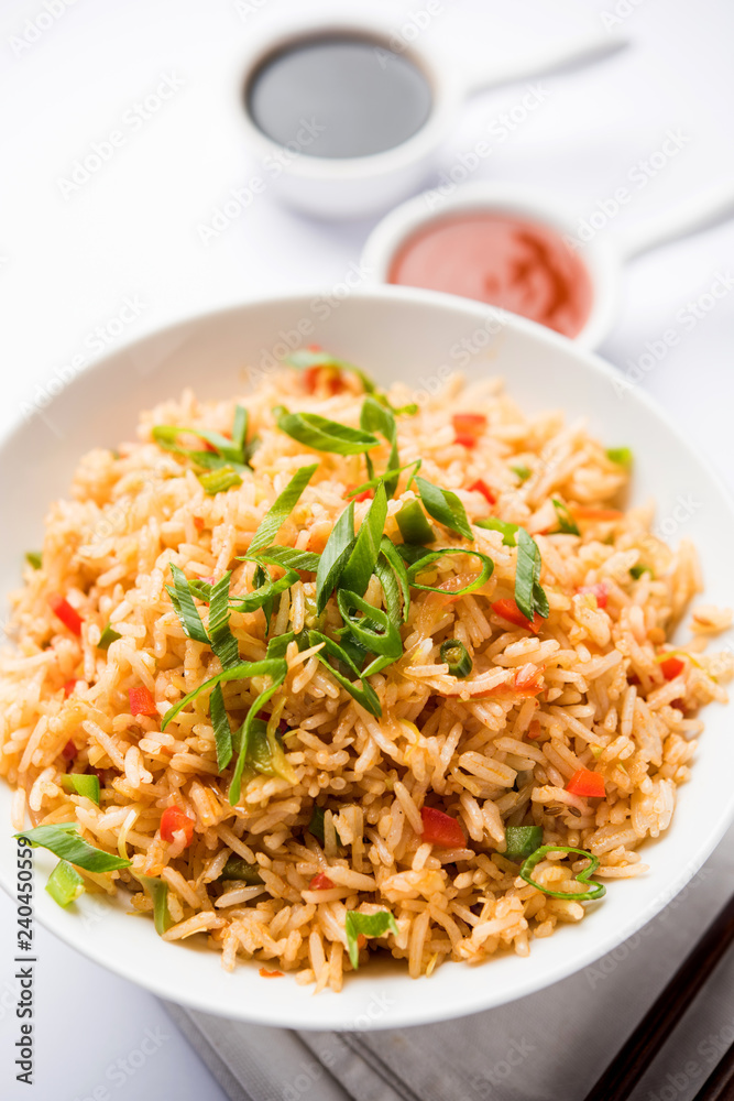 Schezwan Fried Rice Masala is a popular indo-chinese food served in a plate or bowl with chopsticks. selective focus