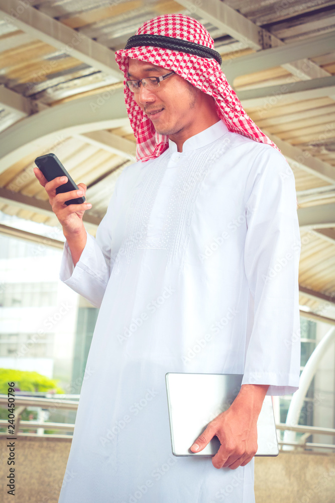   Muslim  Arab man play smart phone and talking on the phone with walking . He smile after call phone.Photo concept partner Business and Technology.