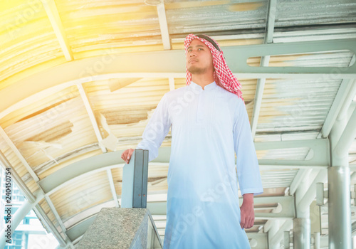 Muslim Arab man. He is holding black business Bag and see the sky. Photo concept with businessman.