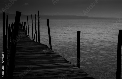 Black White Monochrome old wooden bridge cross path to sea. Concept of alone sadness walk to nowhere without destination and no one help guide the way