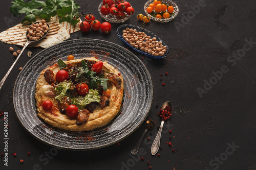 Hummus with vegetables and seafood on black background