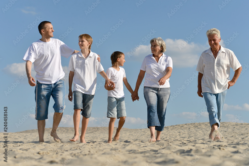 Portrait of grandparents with their grandchildren are walking on the sand Portrait of grandparents with their grandchildren are walking on the sand