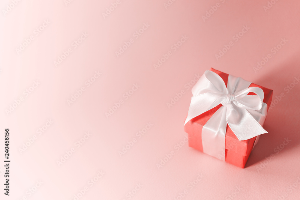 Close view of the box tied with silk ribbon on living coral color pastel background. Gift festive selection. Close view of the box tied with silk ribbon on living coral color pastel background. Gift festive selection.