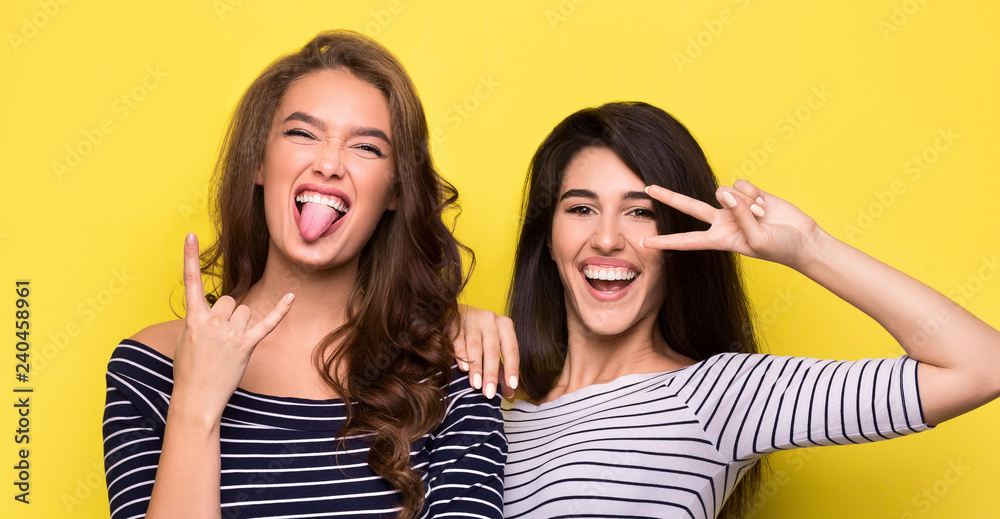 Carefree women fooling around together on yellow background Carefree women fooling around together on yellow background