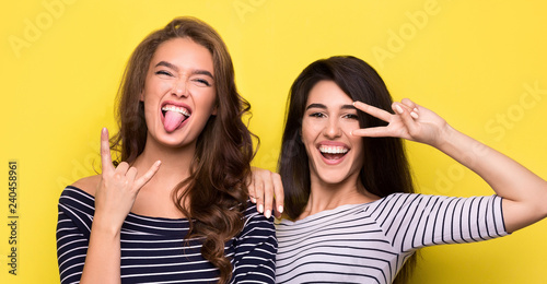 Carefree women fooling around together on yellow background