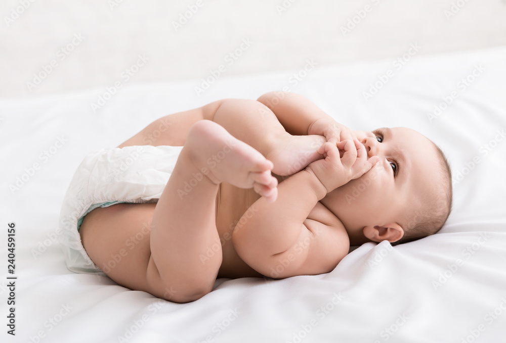Adorable little baby sucking foot lying on bed Adorable little baby sucking foot lying on bed
