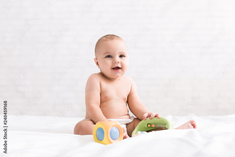 Cute newborn baby playing with toys on bed Cute newborn baby playing with toys on bed