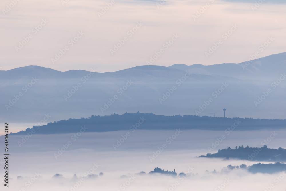 Fog filling a valley in Umbria (Italy), with layers of mountains and hills and various shades of blue