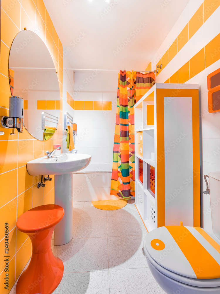 Modern and colorful bathroom. Interior decoration with orange towels and  tiles and vintage furniture from the 70s foto de Stock | Adobe Stock