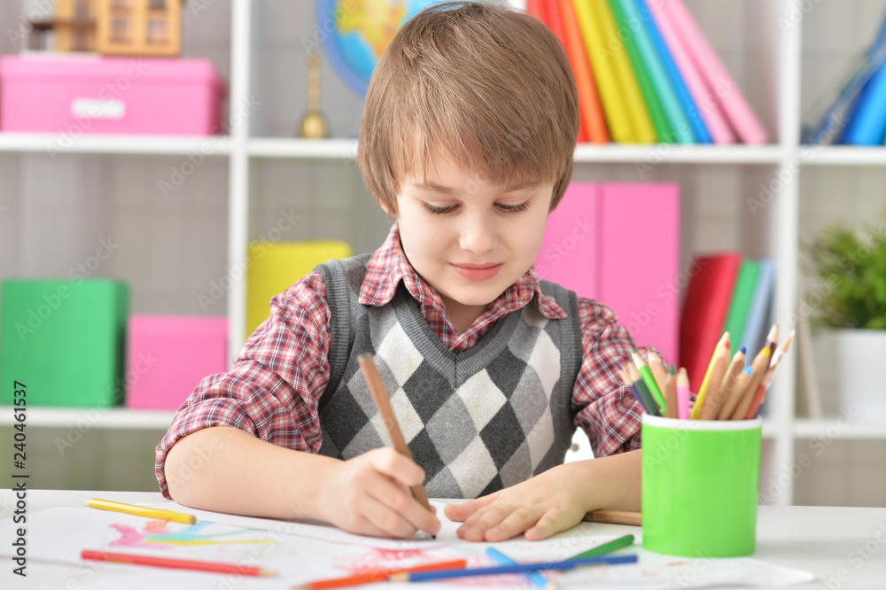 Portrait of little boy sitting at table and drawing with colorful pencils Portrait of little boy sitting at table and drawing with colorful pencils