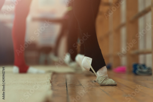 Close up of feet of young girl gymnast rehearsing at the gym club. Close up of a foot of toe-pointing on background of young ballerinas at the dance studio