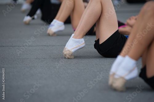 Close up of feet of toe-pointing of young gymnast on the floor in the dance studio. Close up of feet of young gymnast stretching tip toes at the gym club.