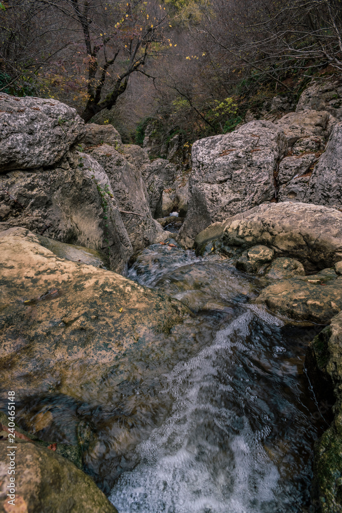 Obraz premium A running river through the rocks of the mountain in autumn.