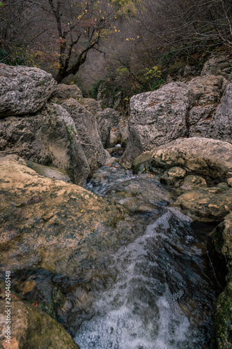 A running river through the rocks of the mountain in autumn.