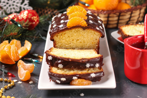 Cupcake with tangerines, covered with chocolate icing is located on the New Year's or Christmas background