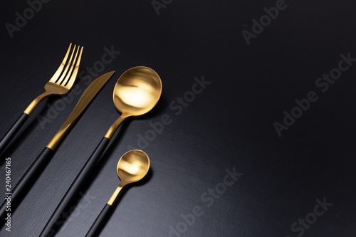 Set of black and gold cutlery on black background photo