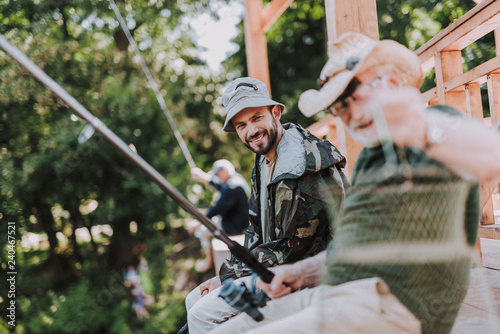 Cheerful bearded man fishing with his father while spending weekend with pleasure