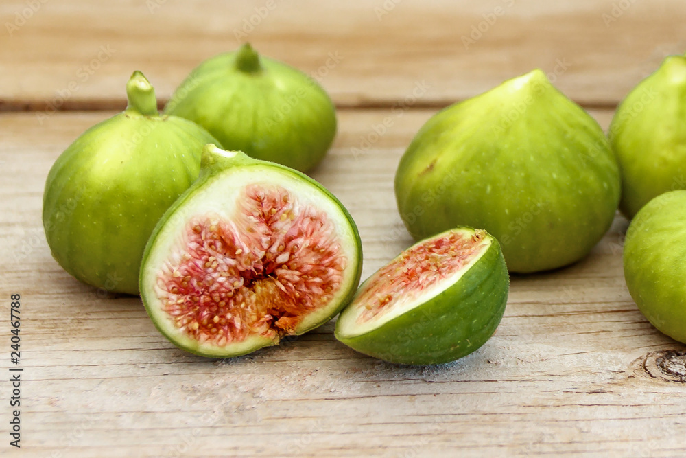 Halved, ripe figs on raw wood table close up