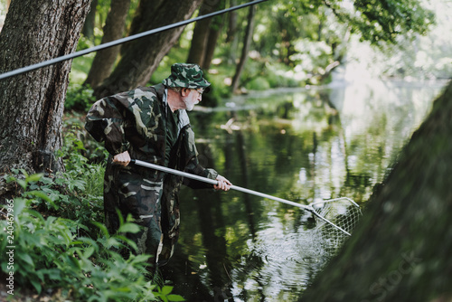Professional aged angler using fishing nets in the river