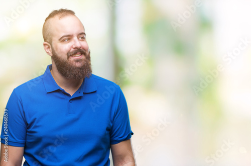 Young caucasian hipster man wearing blue shirt over isolated background smiling looking side and staring away thinking.