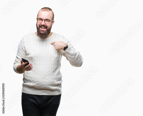 Young caucasian hipster man texting sending message using smartphone over isolated background with surprise face pointing finger to himself