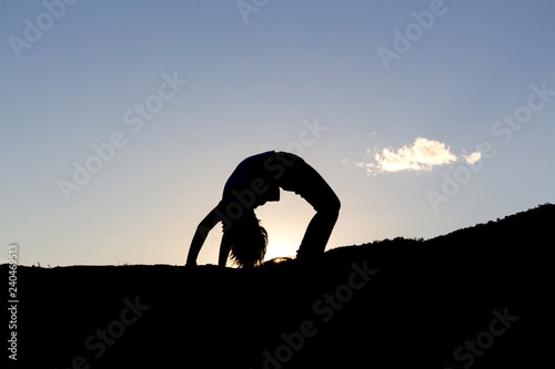 Silhouette of young girl doing yoga at sunset time © AungMyo