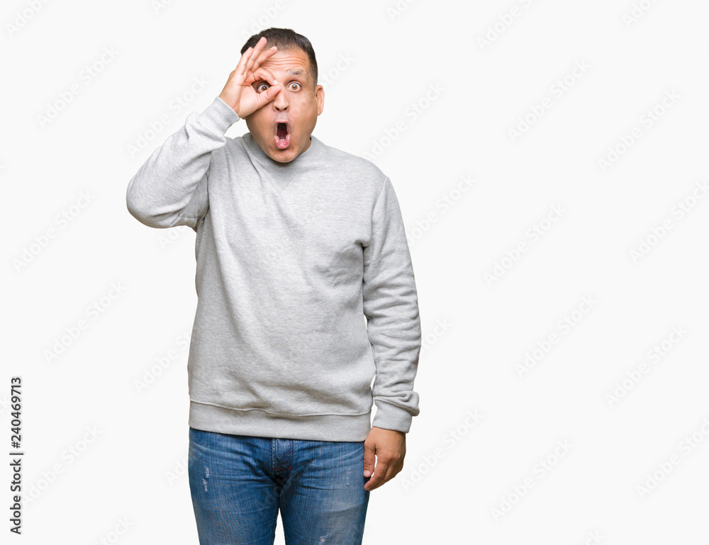 Middle age arab man wearing sport sweatshirt over isolated background doing ok gesture shocked with surprised face, eye looking through fingers. Unbelieving expression. Middle age arab man wearing sport sweatshirt over isolated background doing ok gesture shocked with surprised face, eye looking through fingers. Unbelieving expression.