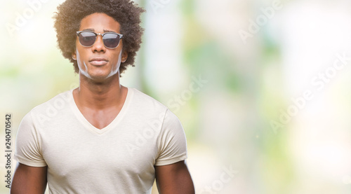 Afro american man wearing sunglasses over isolated background with serious expression on face. Simple and natural looking at the camera.