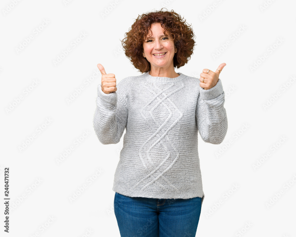 Beautiful middle ager senior woman wearing winter sweater over isolated background success sign doing positive gesture with hand, thumbs up smiling and happy. Looking at the camera