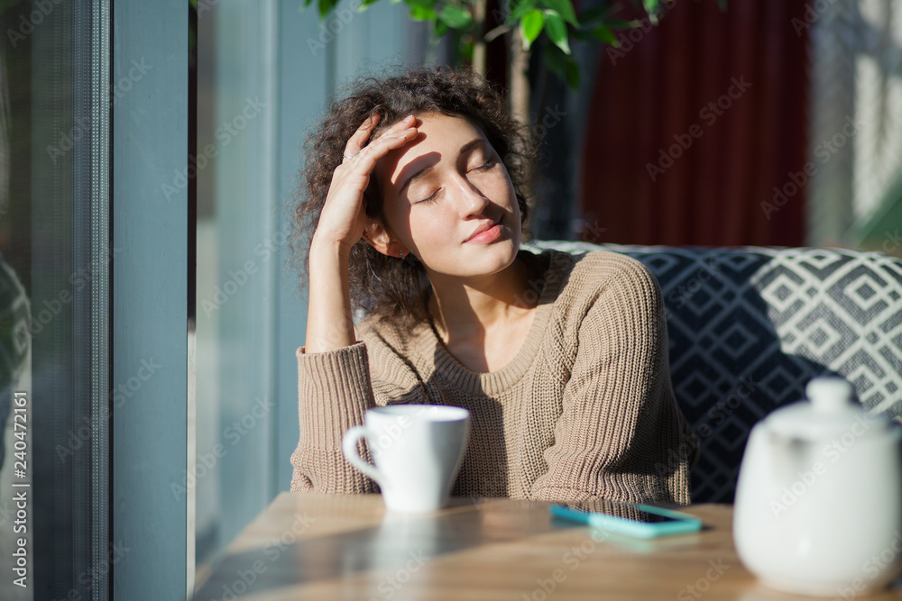 Curly girl in a cafe drinks tea Curly girl in a cafe drinks tea