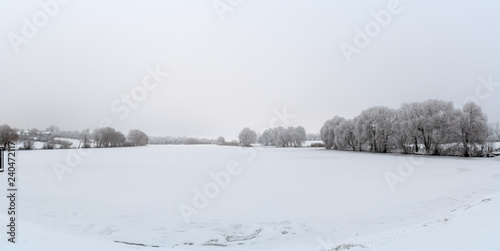 panorama Winter view Trees covered with frost grow on the shores of the lake. © Oleksandr Masnyi