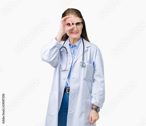 Middle age mature doctor woman wearing medical coat over isolated background doing ok gesture with hand smiling, eye looking through fingers with happy face.