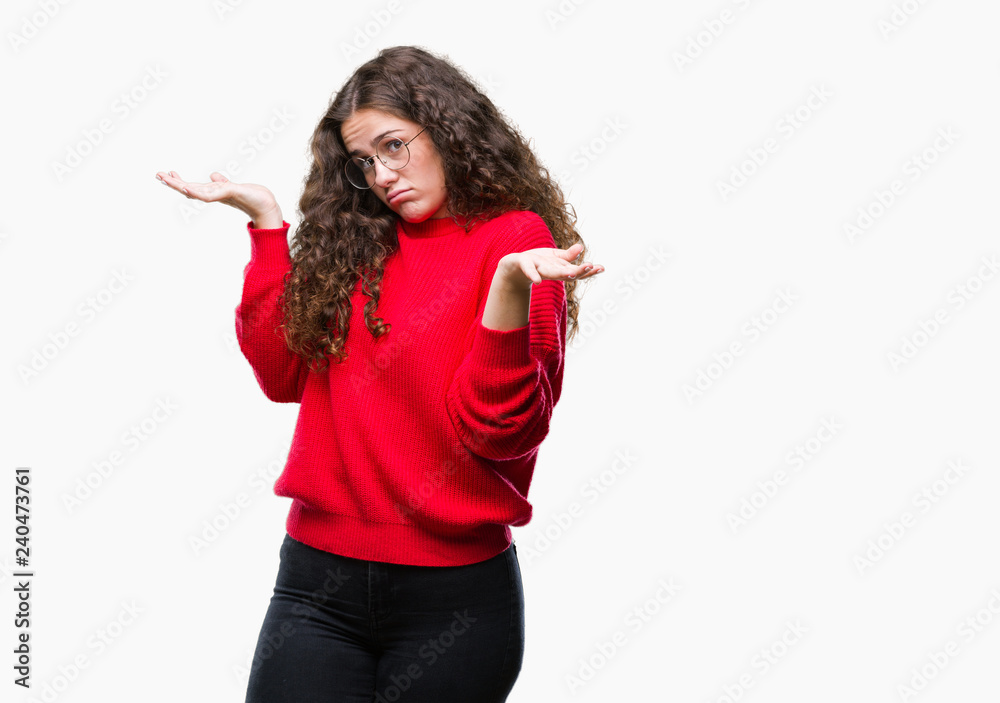 Beautiful brunette curly hair young girl wearing glasses and winter sweater over isolated background clueless and confused expression with arms and hands raised. Doubt concept. Beautiful brunette curly hair young girl wearing glasses and winter sweater over isolated background clueless and confused expression with arms and hands raised. Doubt concept.