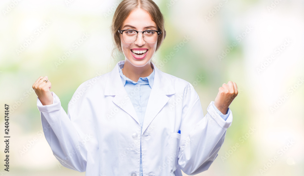 Beautiful young blonde doctor woman wearing white coat over isolated background celebrating surprised and amazed for success with arms raised and open eyes. Winner concept. Beautiful young blonde doctor woman wearing white coat over isolated background celebrating surprised and amazed for success with arms raised and open eyes. Winner concept.