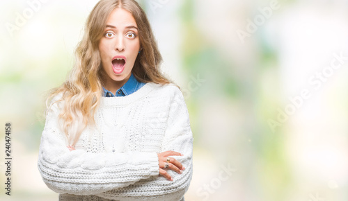 Beautiful young blonde woman wearing winter sweater over isolated background afraid and shocked with surprise expression, fear and excited face. © Krakenimages.com