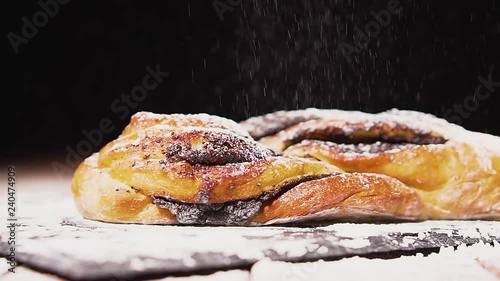 Swirl bun with poppy seeds, sprinkled with flour. Poppy seed braided or roll bread on slate. photo