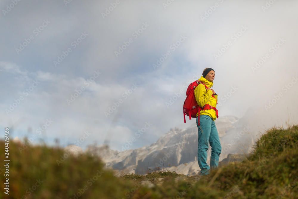 Pretty, young female hiker walking in high mountains (shallow DOF)
