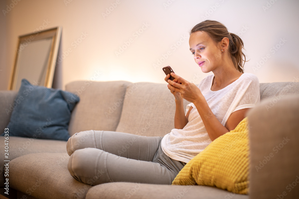 Cute young woman on a comfortable sofa in her modern apartment using her cell phone Cute young woman on a comfortable sofa in her modern apartment using her cell phone