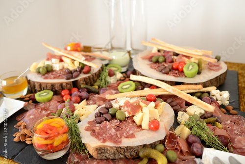 assorted cheeses, jamon and sausages with pickles and olives, on wooden boards