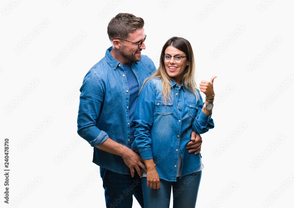 Young couple in love wearing glasses over isolated background smiling with happy face looking and pointing to the side with thumb up. Young couple in love wearing glasses over isolated background smiling with happy face looking and pointing to the side with thumb up.